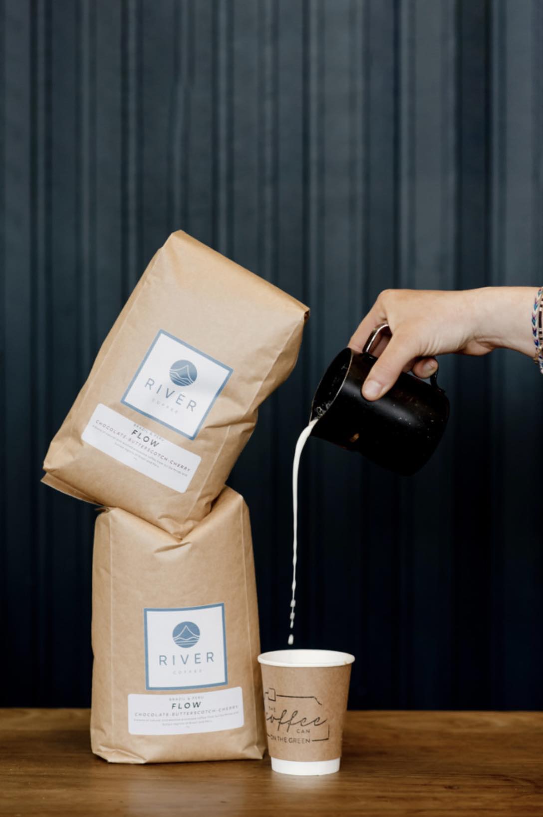 Bags of River Coffee set next to a coffee being poured