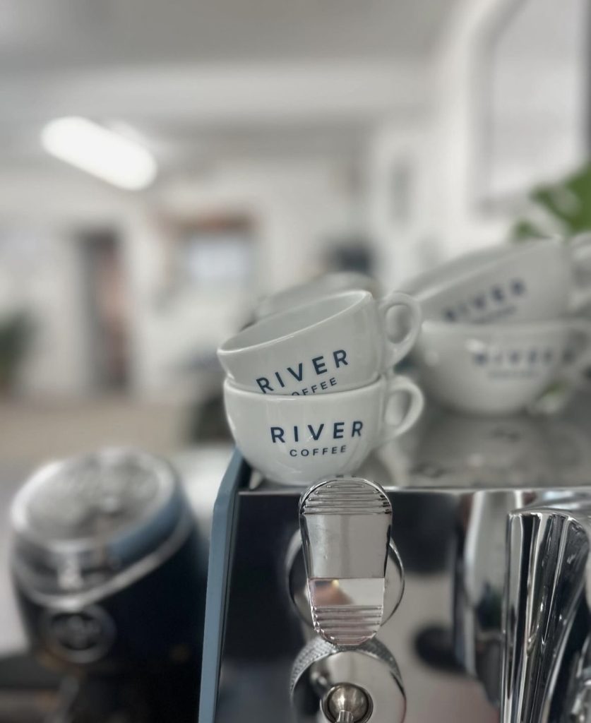 River branded coffee mugs sat on top of the espresso machine